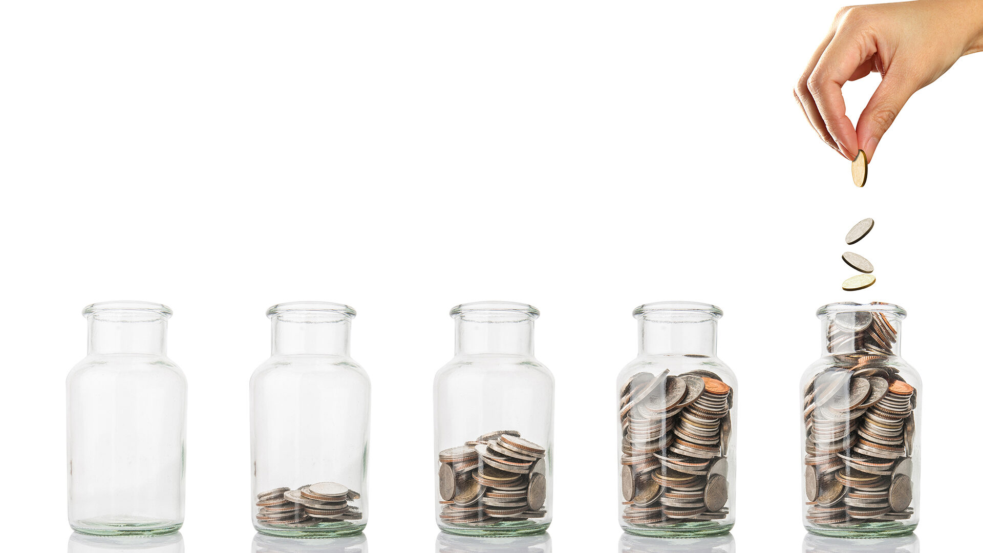 Lady's hand putting money into glass jars.